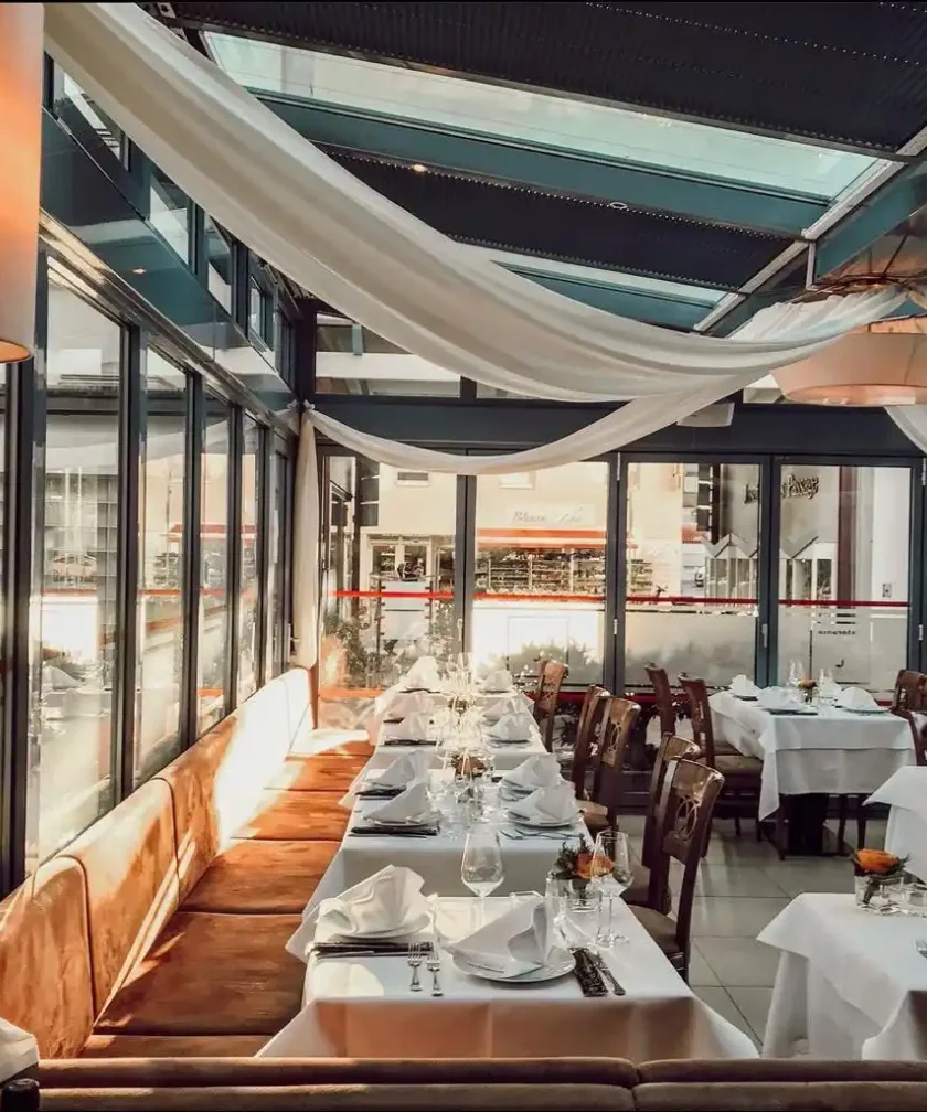 Sonniger Wintergarten des Ristorante Primavera mit liebevoll gedeckten Tischen
