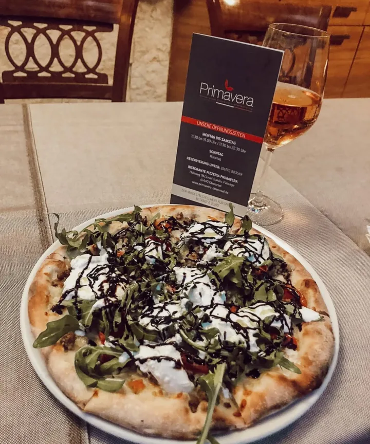 Frisch belegte Pizza auf einem Tisch im Primavera